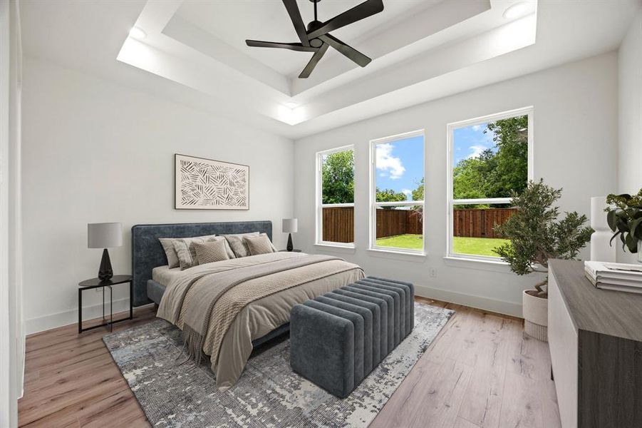 Bedroom with a tray ceiling, light wood finished floors, and baseboards Bedroom with a tray ceiling, light wood finished floors, and baseboards