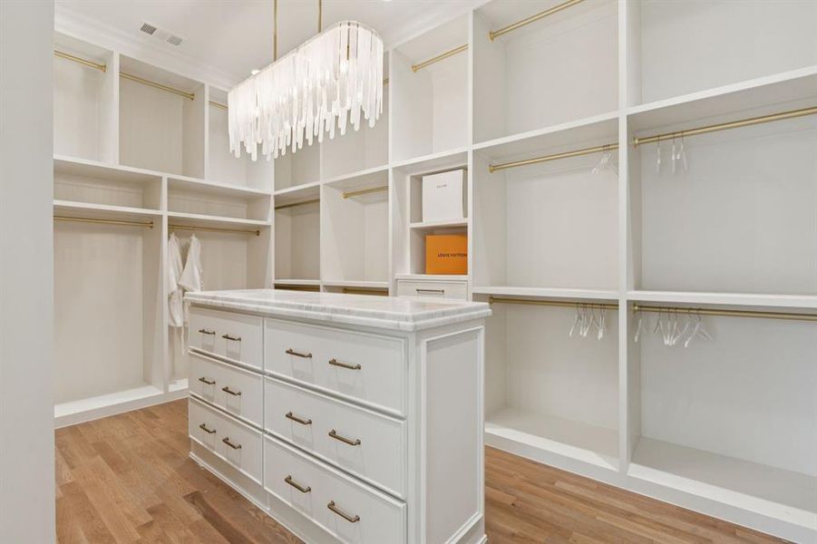 Spacious closet featuring light wood-style floors and a chandelier