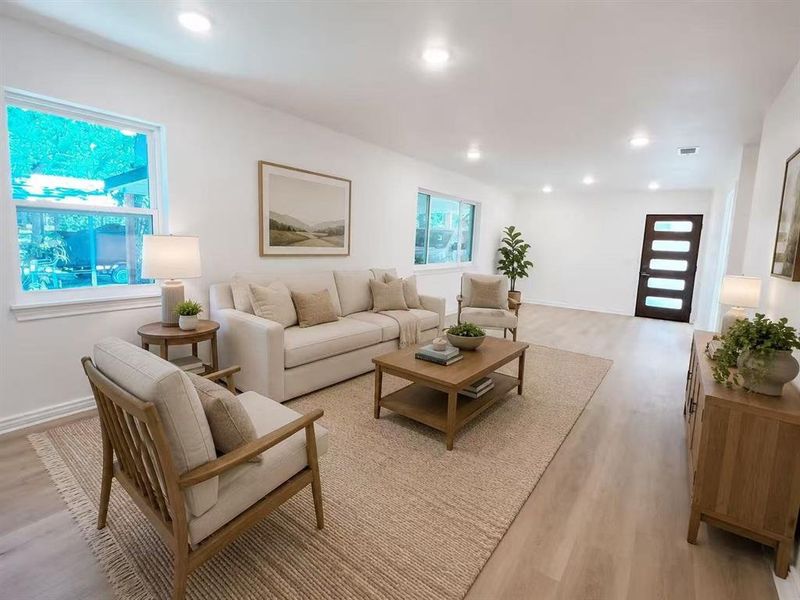 Spacious living area featuring light-toned wood-finish flooring, recessed lighting, and white walls Spacious living area featuring light-toned wood-finish flooring, recessed lighting, and white walls