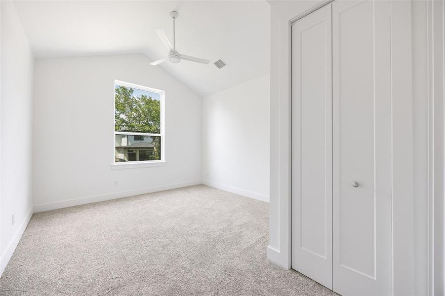 Unfurnished bedroom with lofted ceiling, light carpet, and ceiling fan Unfurnished bedroom with lofted ceiling, light carpet, and ceiling fan