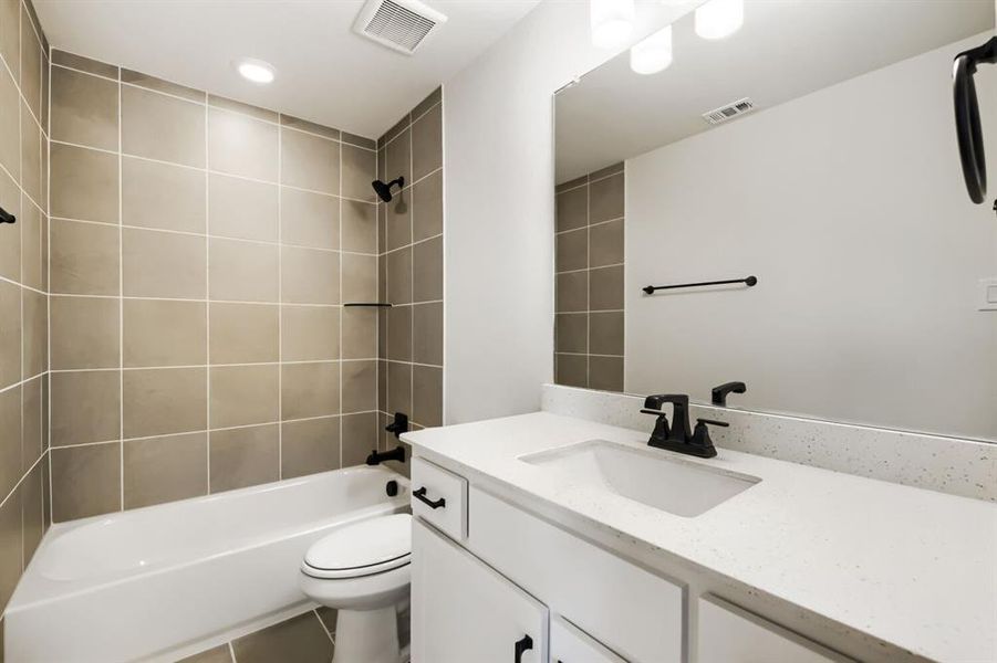 Bathroom featuring a white vanity with a light-colored countertop, an integrated sink, and matte black fixtures Bathroom featuring a white vanity with a light-colored countertop, an integrated sink, and matte black fixtures