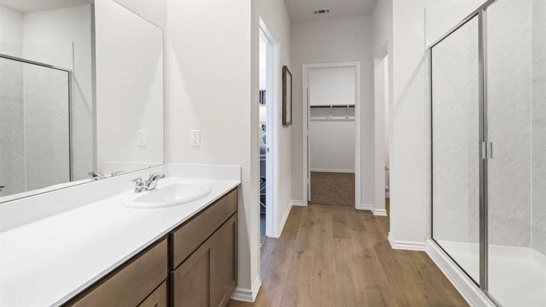 Full bathroom featuring a walk in closet, a stall shower, dark wood-type flooring, and vanity
