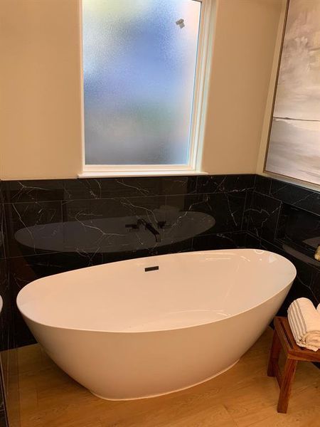 Bathroom featuring tile walls, flooring, and a bath