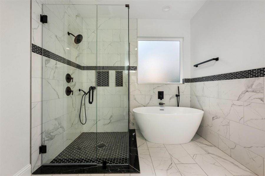 Bathroom featuring a shower stall, a soaking tub, tile walls, and marble finish floors