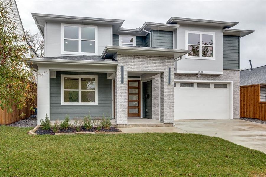 View of front of home featuring brick siding, driveway, and a garage