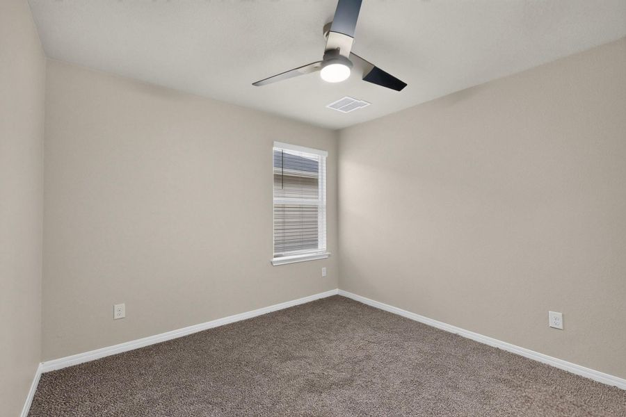 Plush carpeting and a classic single window create a comfortable, inviting secondary bedroom.