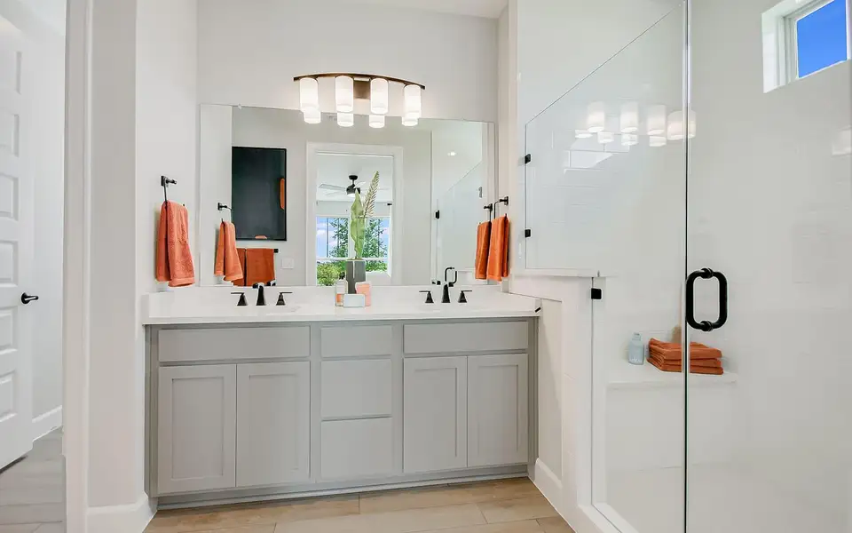 Bathroom with healthy amount of natural light, double vanity, a shower stall, and light wood finished floors