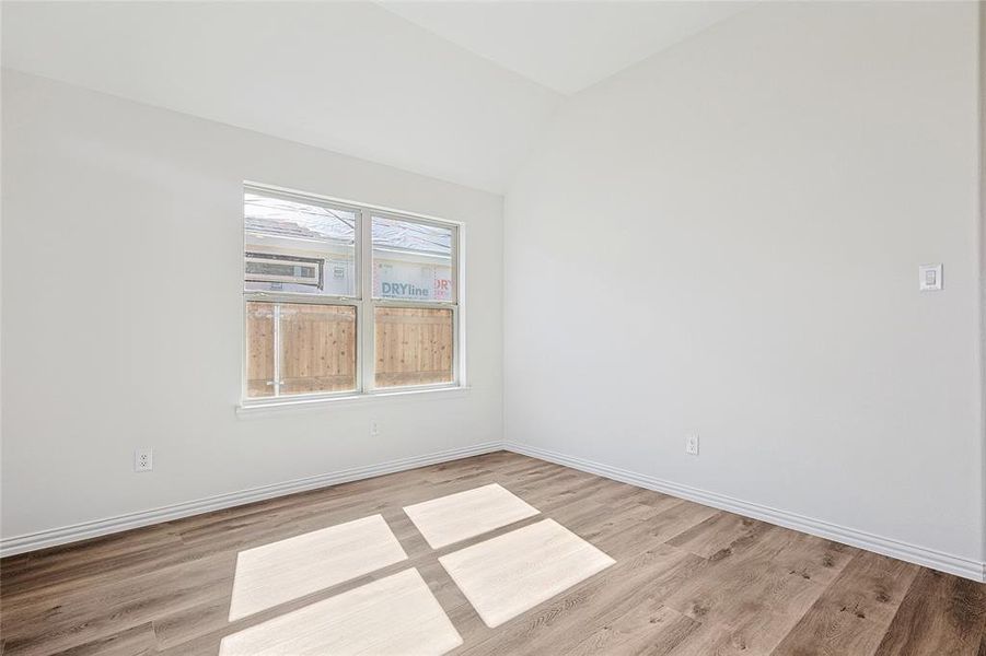 Spare room featuring lofted ceiling and light wood-type flooring