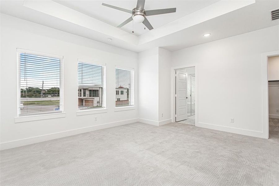 Unfurnished bedroom featuring a tray ceiling, carpet flooring, a ceiling fan, and recessed lighting