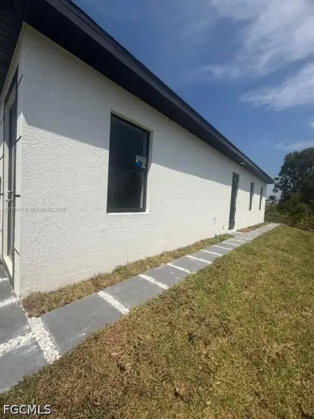 Stucco exterior featuring dark-trimmed window frames, contrast fascia boards, and a stone paver walkway bordered by white gravel Stucco exterior featuring dark-trimmed window frames, contrast fascia boards, and a stone paver walkway bordered by white gravel