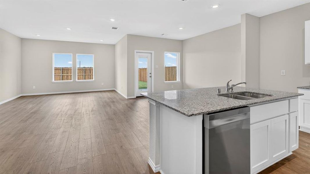 Kitchen island featuring a double basin stainless steel sink, stainless steel dishwasher, and granite countertop