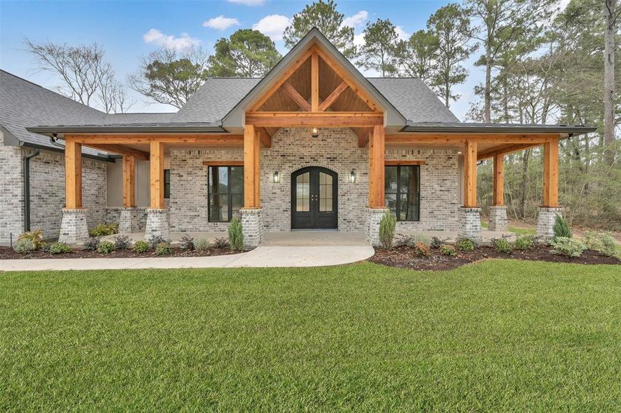 A beautiful view of your front porch.  The Cedar beams accent your iron doors well!