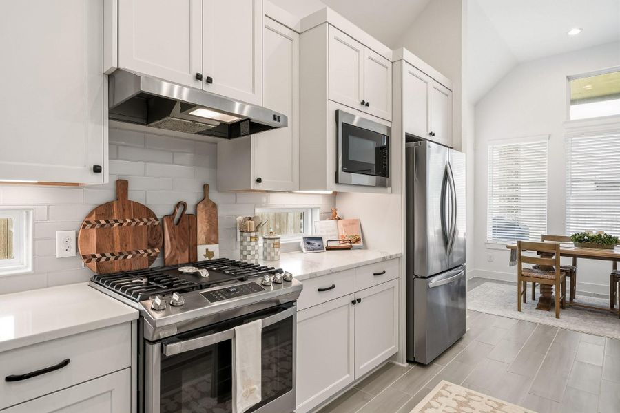 The kitchen is well-appointed with a GE stainless steel range featuring four gas burners and a built-in griddle, complemented by a GE Profile microwave for a sleek, well-equipped cooking space.