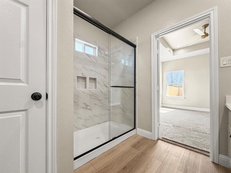 Full bath featuring vanity, a marble finish shower, and light wood-type flooring
