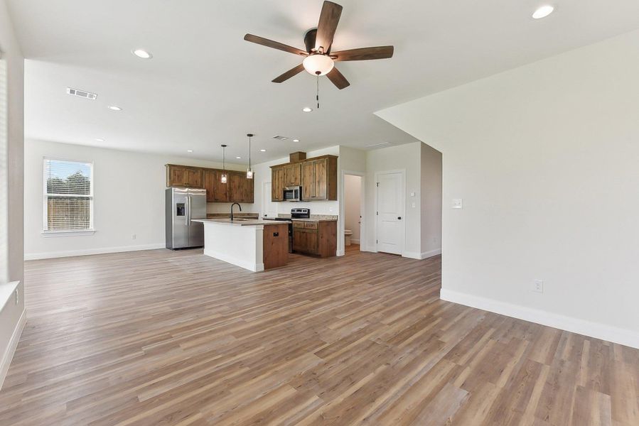 Kitchen with stainless steel appliances, light wood-style flooring, a kitchen island with sink, open floor plan, and visible vents