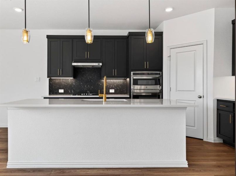 Kitchen featuring dark cabinets, recessed lighting, dark wood-type flooring, decorative light fixtures, and backsplash