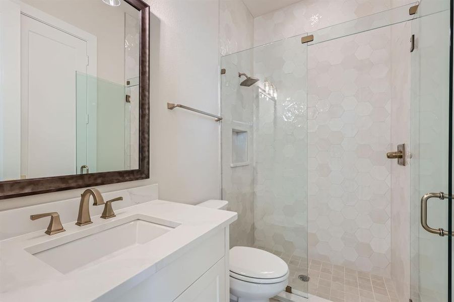 Bathroom featuring a shower with door, vanity, and toilet