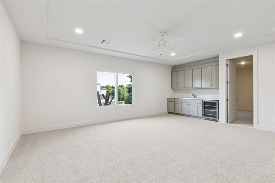 Unfurnished living room with light carpet, recessed lighting, beverage cooler, and ceiling fan