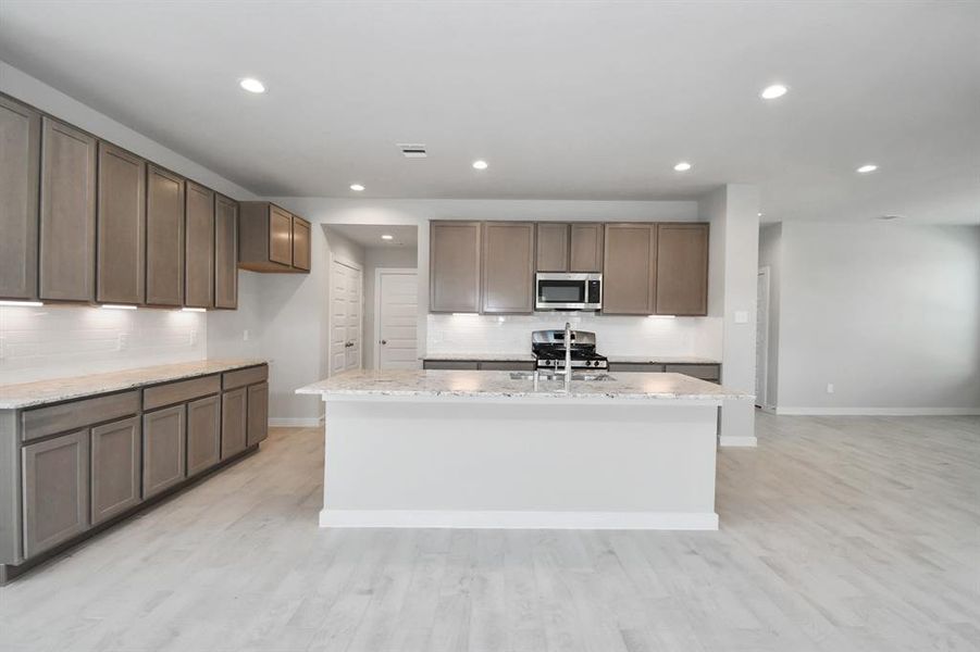 Discover another perspective of this stunning kitchen, generously appointed with an abundance of counter space. Sample photo of completed home with similar floor plan. As-built interior colors and selections may vary.