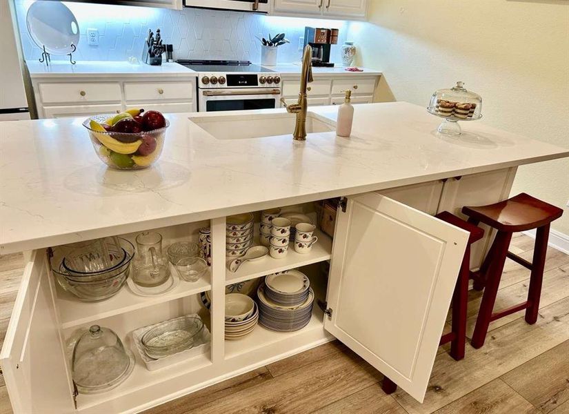 Kitchen featuring tasteful backsplash, stainless steel range with electric stovetop, white cabinetry, light stone countertops, and light hardwood / wood-style floors