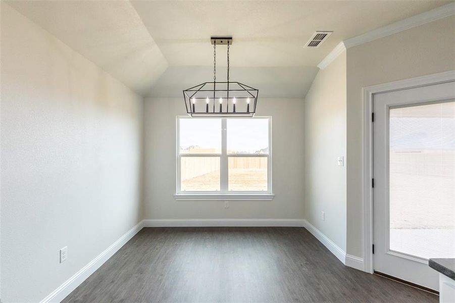 Open-concept room featuring wood-finish flooring, a contemporary geometric chandelier, and crown molding
