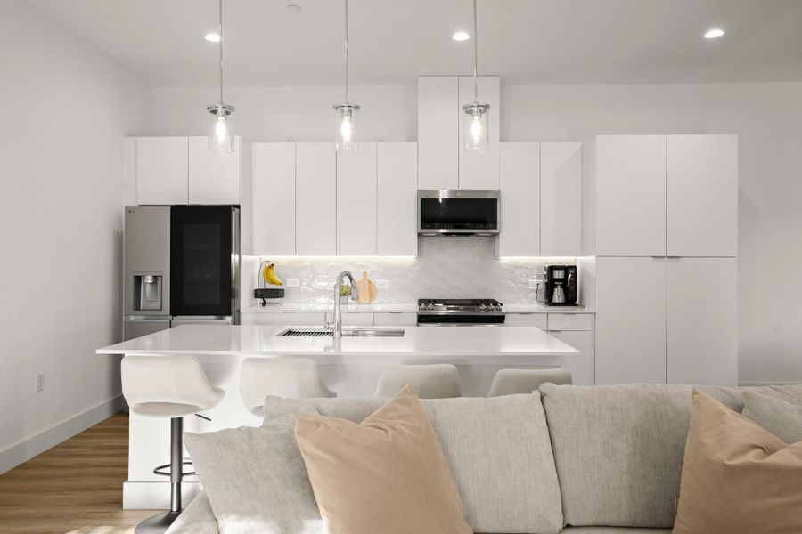 A sleek modern island kitchen comes ready to use with stainless appliances, quartz countertops, and chic contemporary finishes. A sleek modern island kitchen comes ready to use with stainless appliances, quartz countertops, and chic contemporary finishes.