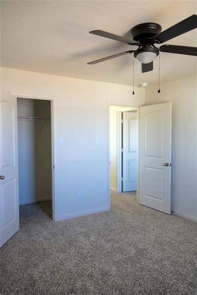 Unfurnished bedroom featuring carpet floors, a textured ceiling, a closet, and ceiling fan