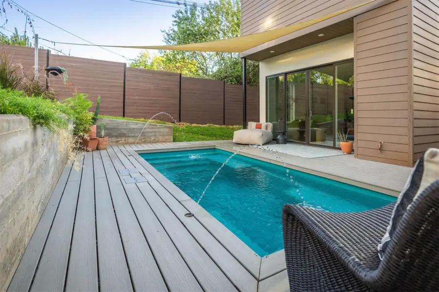 An inviting backyard pool is bordered by composite decking and a privacy fence. An inviting backyard pool is bordered by composite decking and a privacy fence.