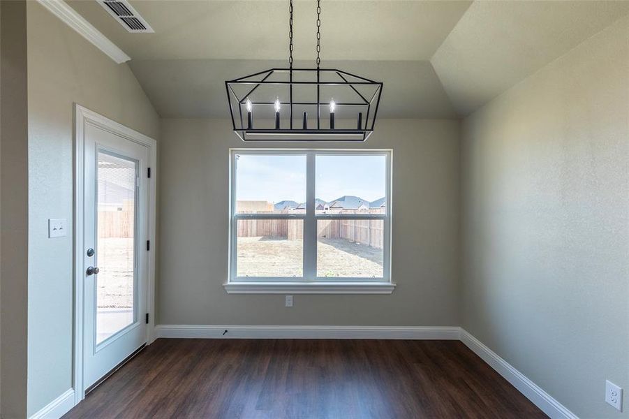 Room featuring wood-finish flooring, a contemporary geometric chandelier, a large exterior window, and a glass-paneled door