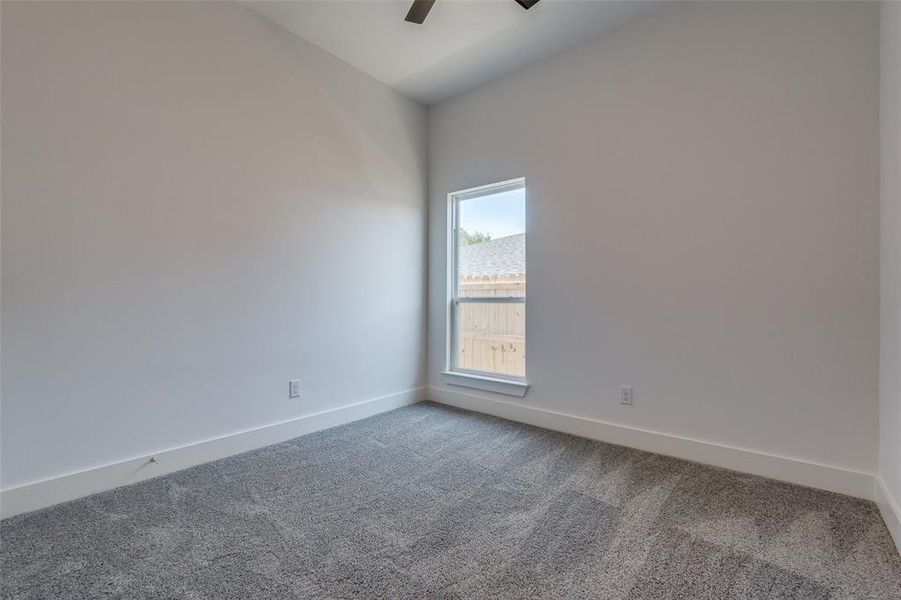 Carpeted empty room featuring ceiling fan and vaulted ceiling