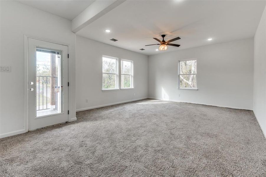 Carpeted spare room featuring a wealth of natural light and ceiling fan