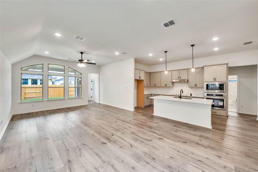 Kitchen featuring stainless steel oven, built in microwave, light countertops, open floor plan, and tasteful backsplash Kitchen featuring stainless steel oven, built in microwave, light countertops, open floor plan, and tasteful backsplash