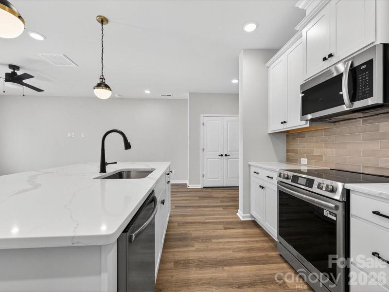 Open kitchen features 42" cabinets with soft close doors & drawers with large kitchen shiplap Island, quartz countertops, single bowl SS sink, tiled backsplash, Frigidaire gallery range appliances which are vented to outside of the home. Large walk-in pantry with solid shelving.