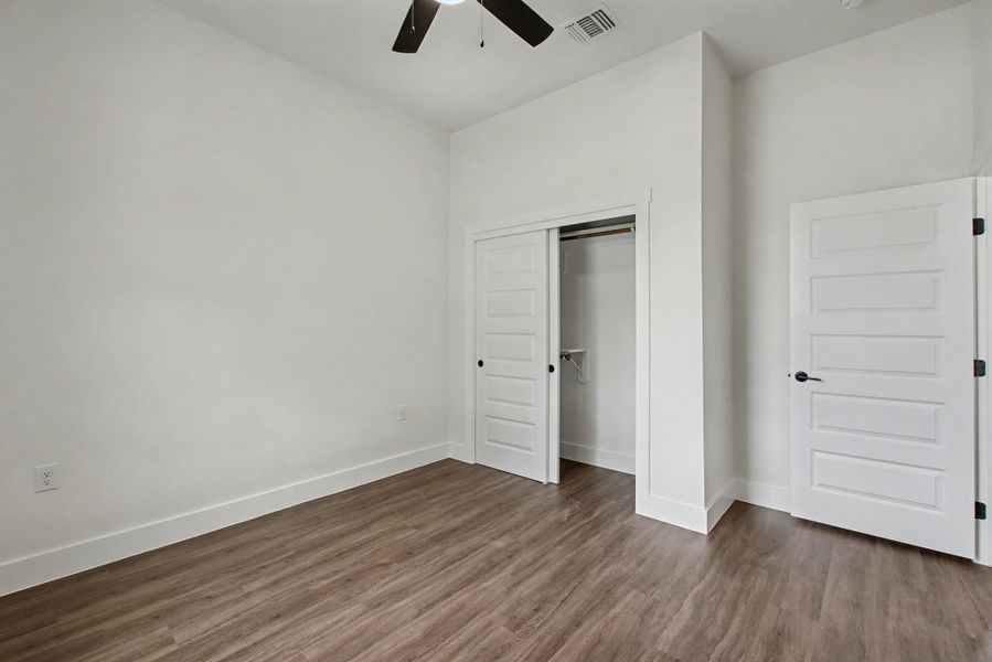 Unfurnished bedroom featuring dark wood finished floors, a closet, and ceiling fan
