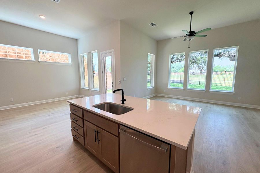 A pristine kitchen island with integrated sink anchors this naturally illuminated open-concept living space. A pristine kitchen island with integrated sink anchors this naturally illuminated open-concept living space.