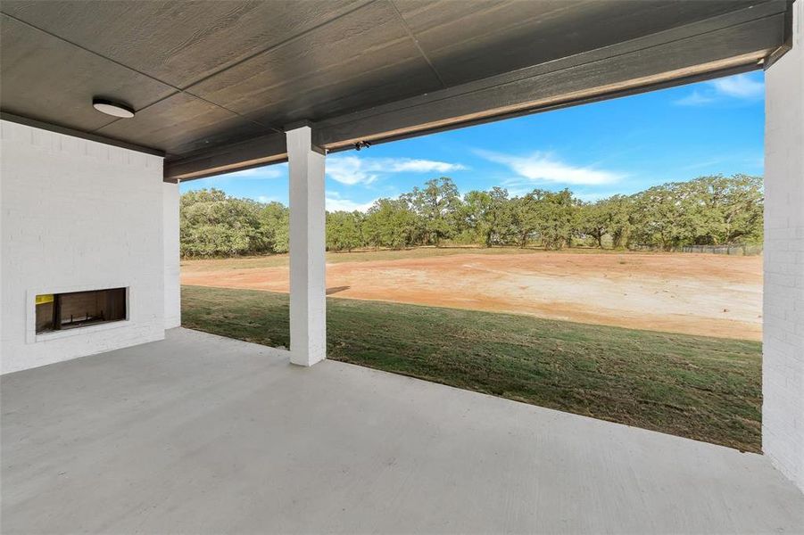 View of patio with an outdoor brick fireplace