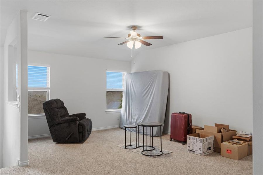 Carpeted room featuring multiple windows, a ceiling fan with integrated lighting, and neutral wall finishes