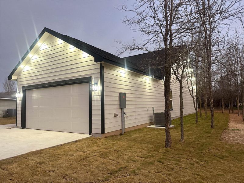 View of side of property featuring driveway and a yard