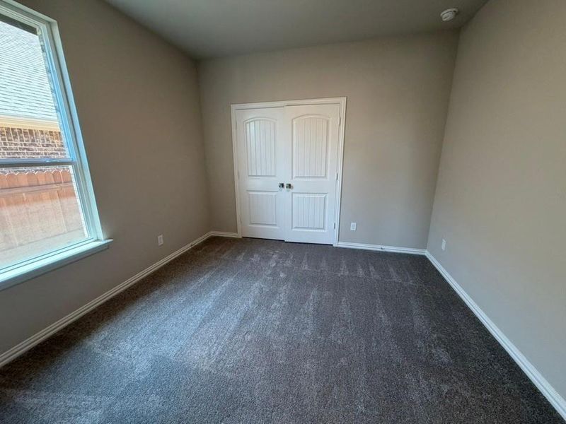 Room featuring neutral wall tones, textured carpeting, and white baseboards