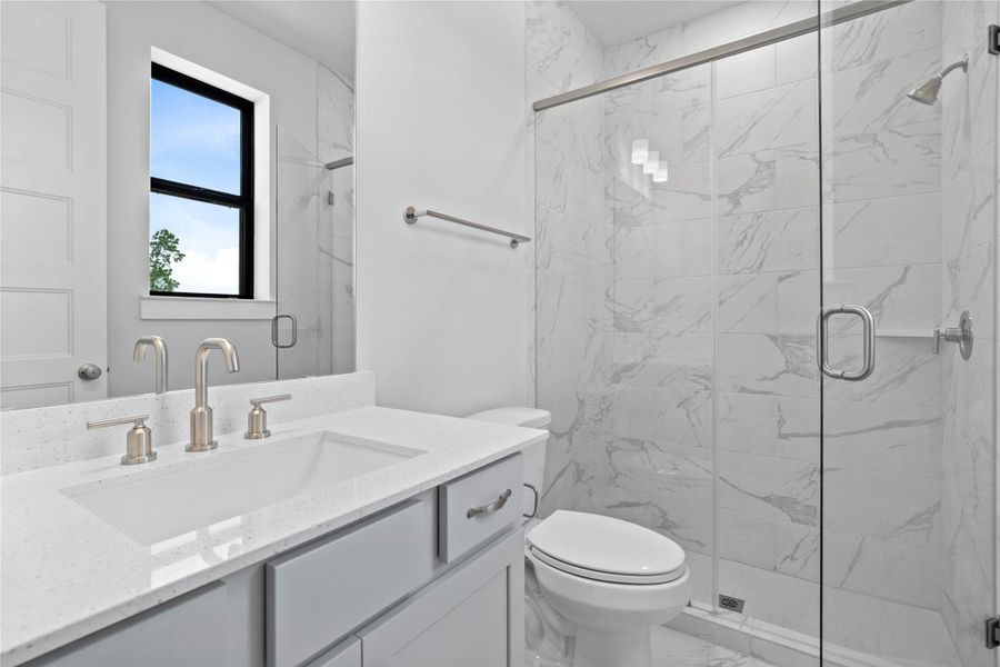 The private en suite bathroom features a modern vanity with light countertop, and a walk-in shower with sleek tile surround.