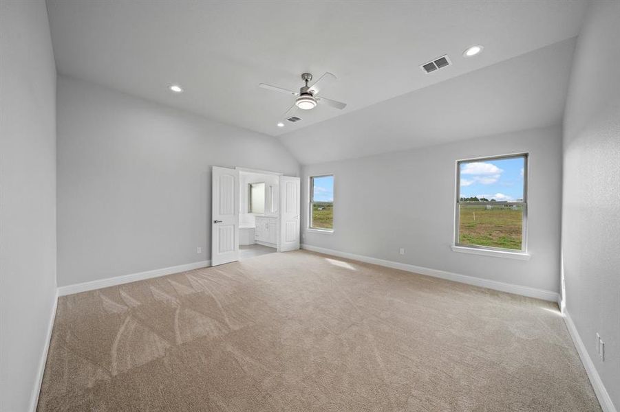 Spare room featuring light carpet, lofted ceiling, and ceiling fan