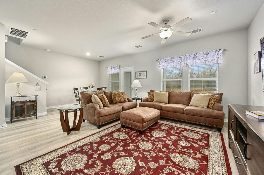 Living room with light hardwood / wood-style floors and ceiling fan