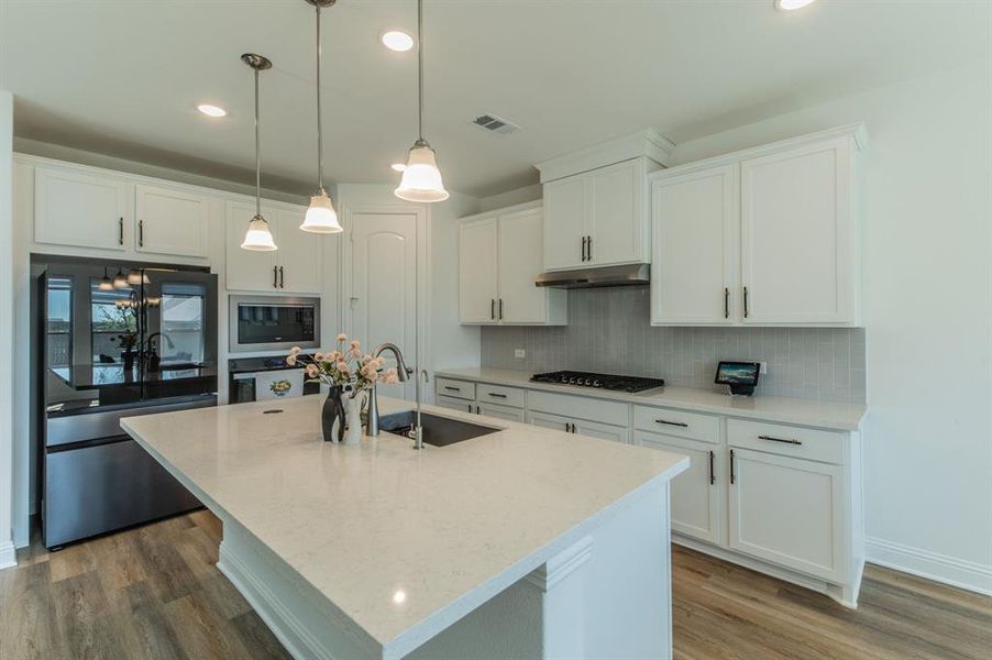 Modern kitchen featuring white shaker cabinetry and a light-toned countertop island with a built-in sink