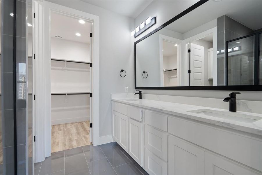 Bathroom featuring vanity, tile patterned flooring, and a shower with door