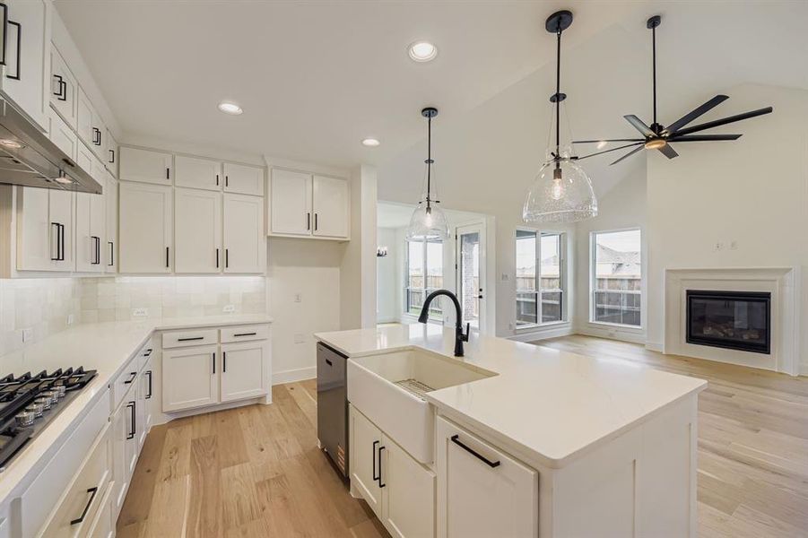 Kitchen featuring light wood finished floors, white cabinetry, hanging light fixtures, recessed lighting, and a center island with sink Kitchen featuring light wood finished floors, white cabinetry, hanging light fixtures, recessed lighting, and a center island with sink