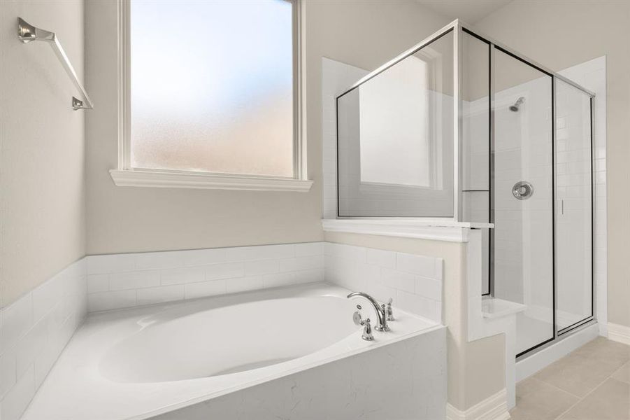 This additional view of your primary bathroom features tile flooring, fresh paint, walk-in shower, a separate garden tub, and a large walk-in closet.