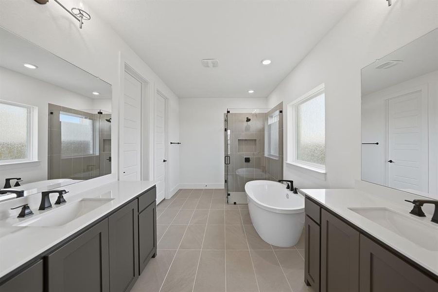Full bath with a freestanding tub, a stall shower, two vanities, light tile patterned floors, and recessed lighting Full bath with a freestanding tub, a stall shower, two vanities, light tile patterned floors, and recessed lighting