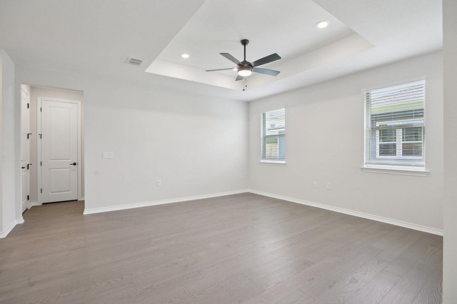 Unfurnished room featuring a tray ceiling, light wood-style flooring, recessed lighting, and a ceiling fan