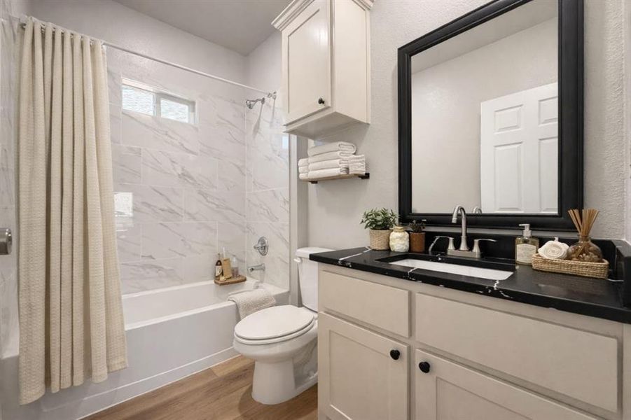 Bathroom with vanity, shower / tub combo, and light wood-style floors