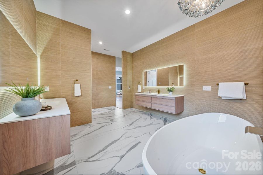 Textured tile surrounds the space, heated floors and dual vanities